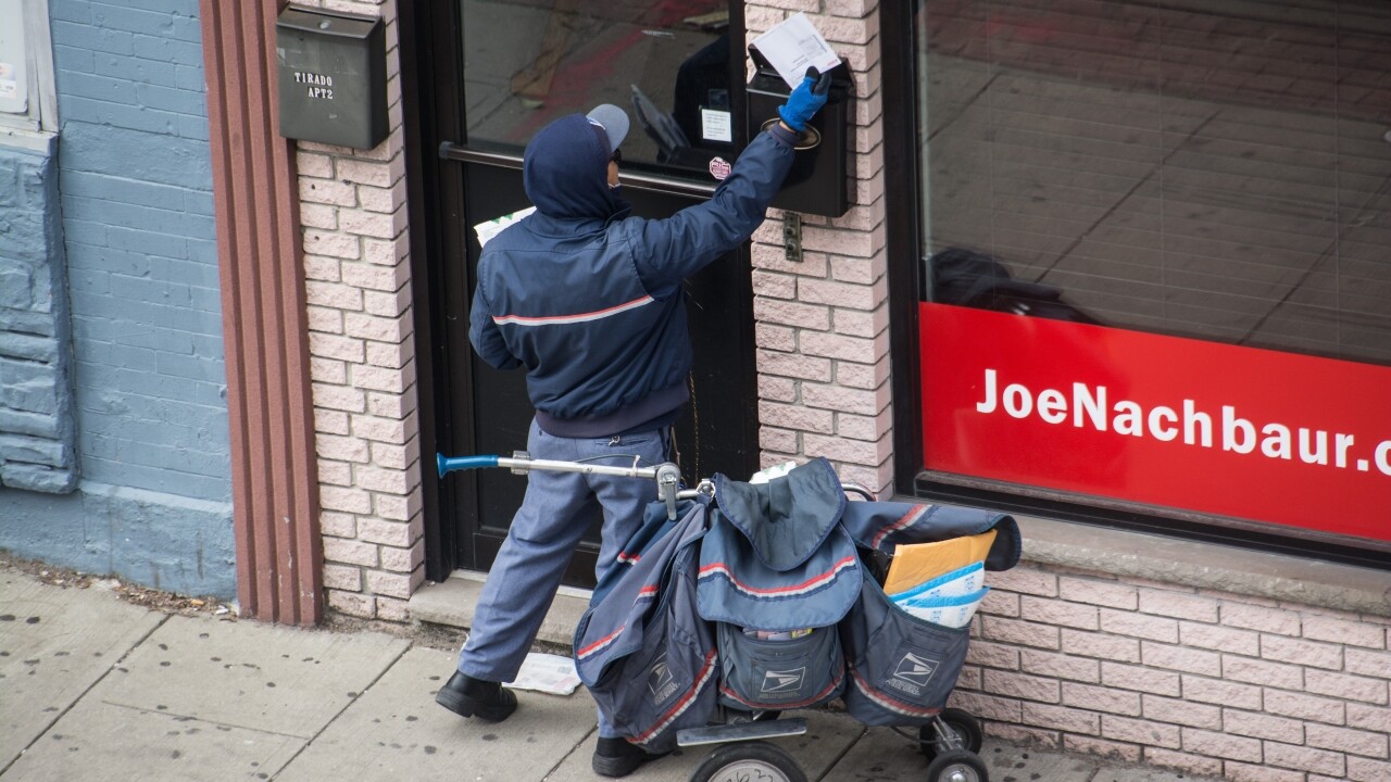 Postal worker puts mail in a mailbox